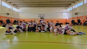Formazione dell'Amicizia Volley festeggia sul campo dopo una vittoria.