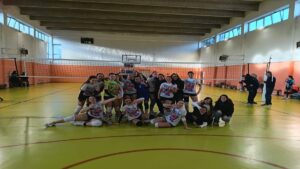 Formazione dell'Amicizia Volley festeggia sul campo dopo una vittoria.