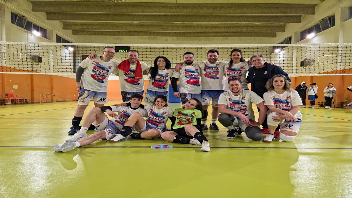 Formazione dell'Amicizia Volley festeggia sul campo dopo una vittoria.